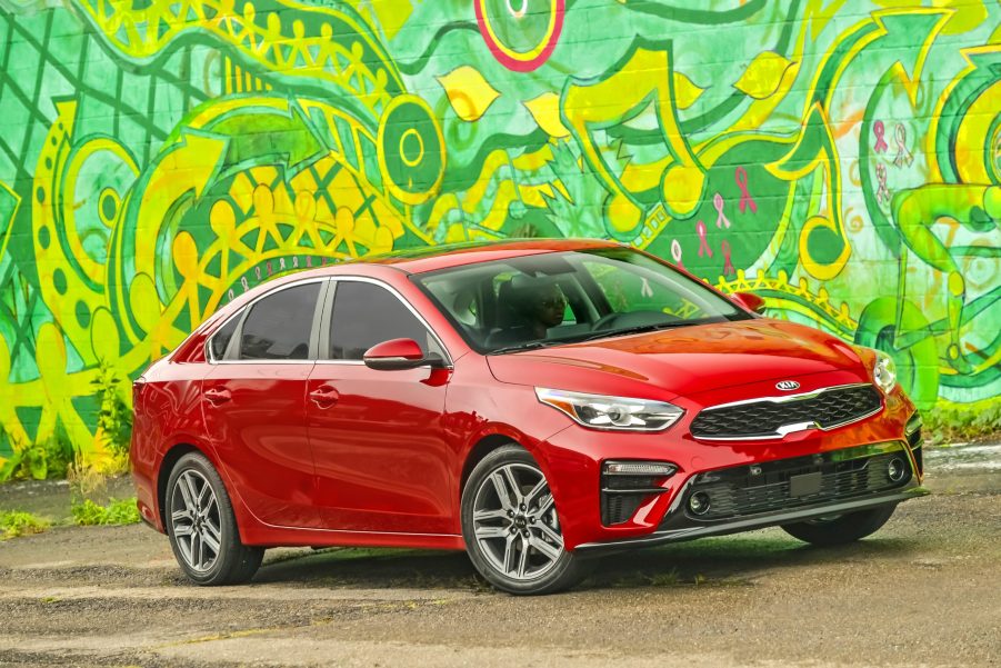 A red 2021 Kia Forte parked next to an artsy green wall