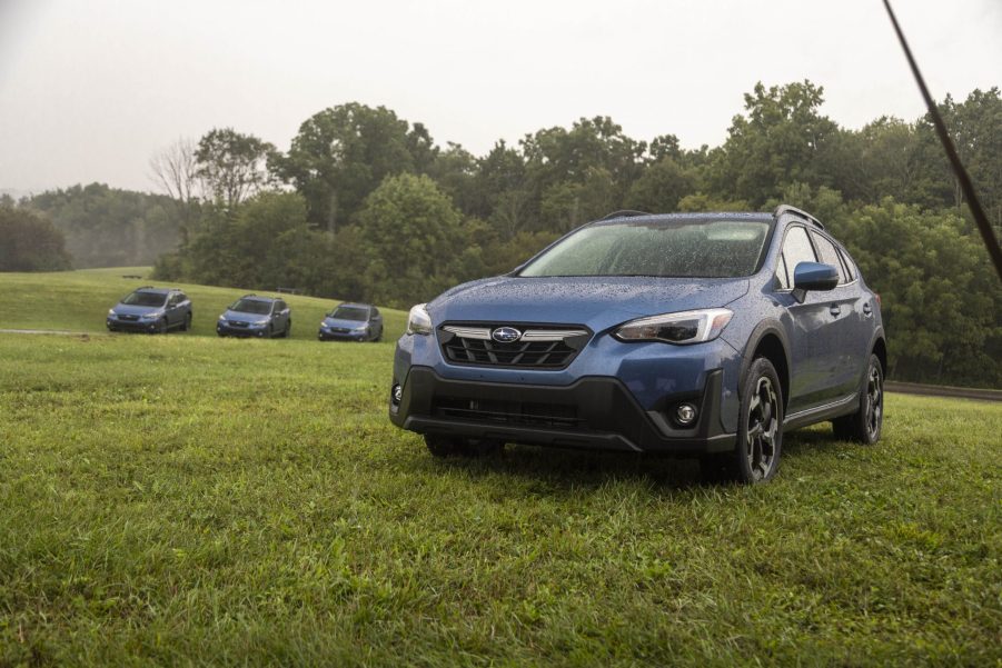 A blue 2021 Subaru Crosstrek Limited parked in the grass for a photoshoot with 3 other Subarus in the far-off distance