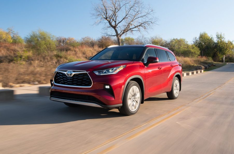 A red 2021 Toyota Highlander Hybrid driving down a road