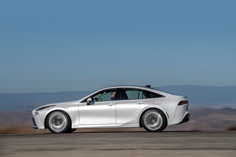 A 2021 Toyota Mirai Limited in Oxygen White traveling on asphalt with a mountain backdrop