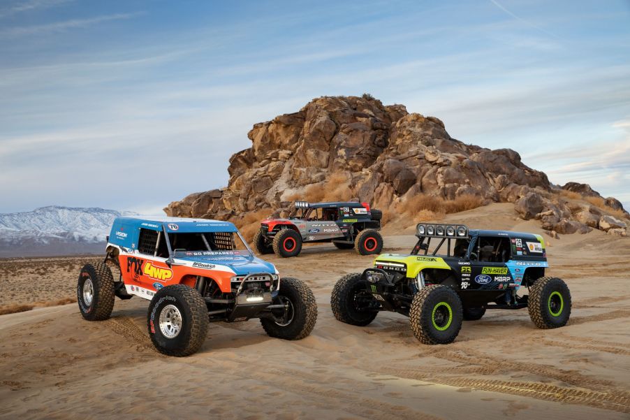 The three 2021 Ford Bronco 4400 King of the Hammers racers gathered around a desert rock formation