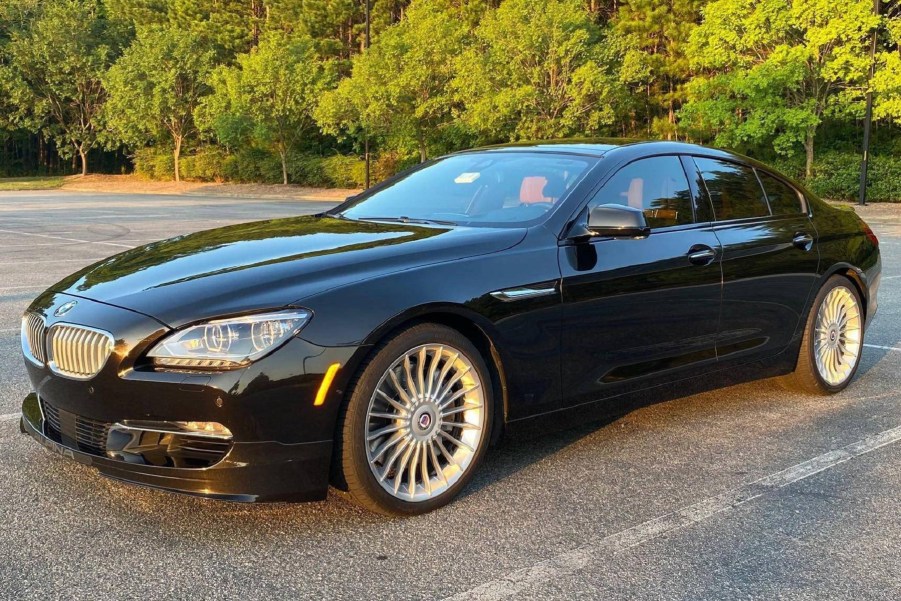 A black 2015 BMW Alpina B6 xDrive Gran Coupe parked on a sunset-lit tree-lined parking lot