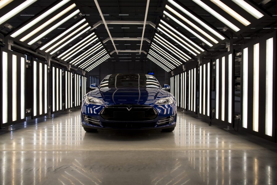 A blue 2015 Tesla Model S electric sedan under rows of lights