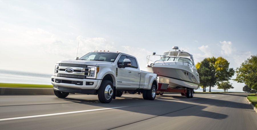 A white 2018 Ford Super Duty Limited towing a white boat on the highway