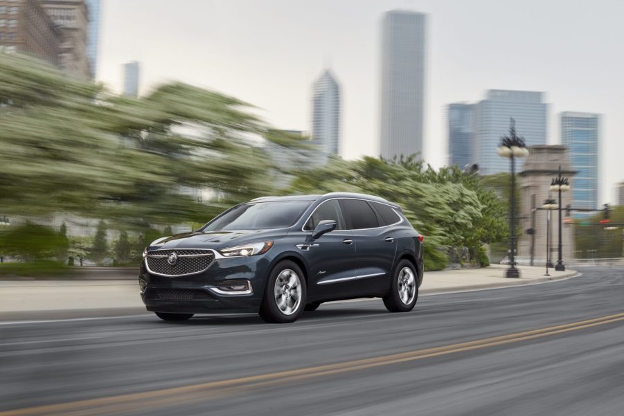 A dark blue 2021 Buick Enclave luxurious midsize SUV driving down a highway road