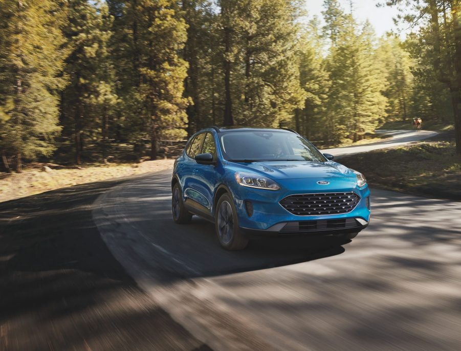 The 2021 Ford Escape in blue driving along a winding road with trees in the background