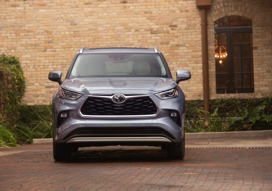 A silver 2021 Toyota Highlander midsize crossover SUV parked in the red-brick driveway of a tan-brick building