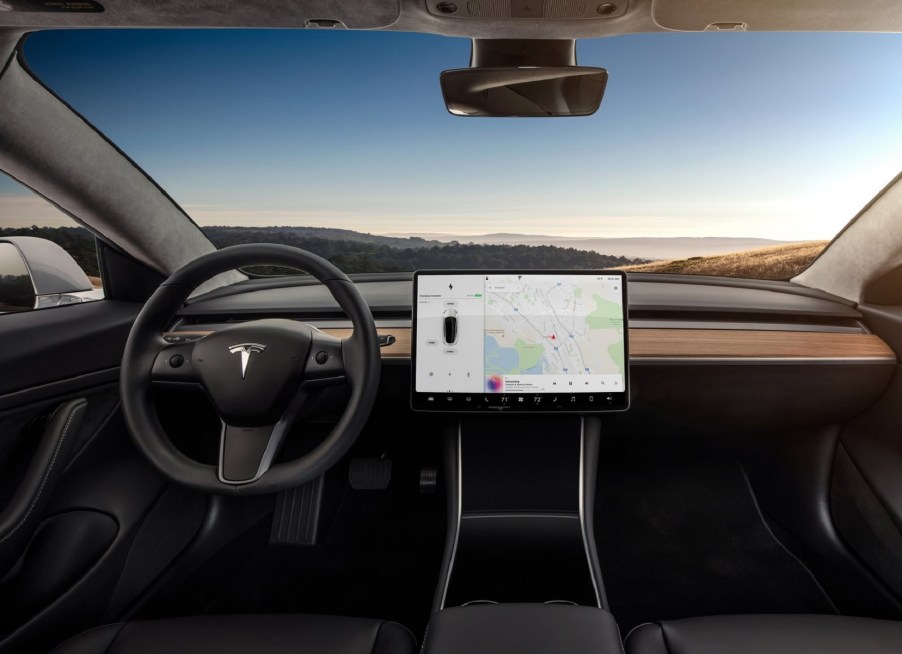 The black front seats and wood-trimmed dashboard of a 2018 Tesla Model 3