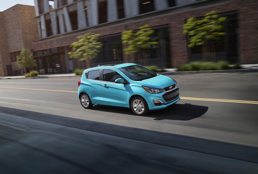 a blue Chevy Spark driving on a city street