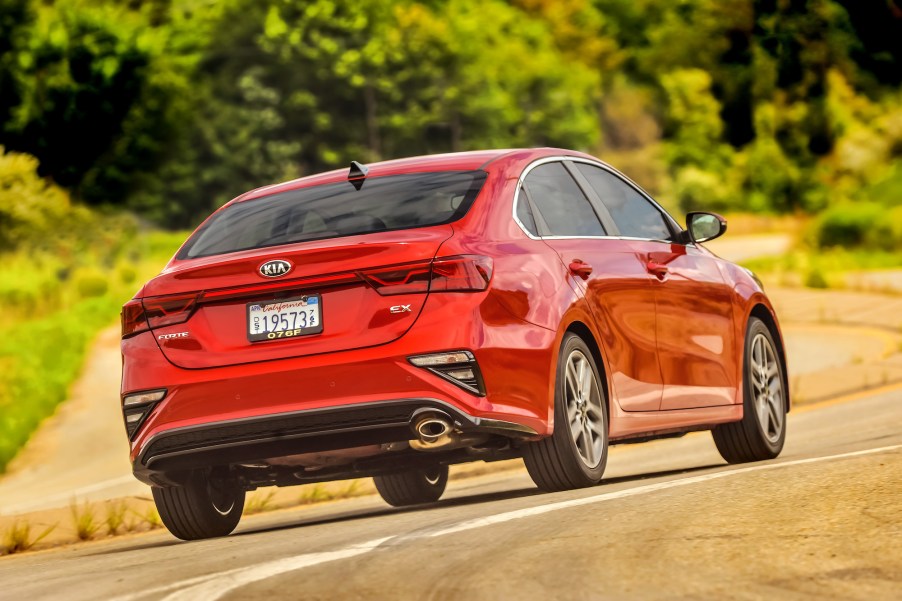 A red 2021 Kia Forte compact car traveling on a rural road