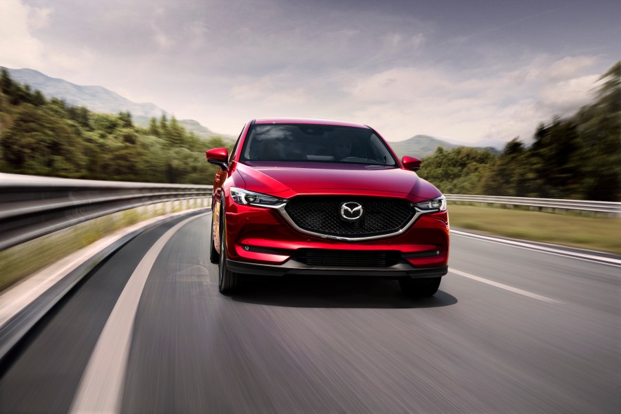 Front view of a red 2021 Mazda CX-5 compact SUV traveling on a two-lane mountain highway