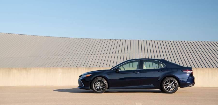 A navy-blue 2021 Toyota Camry XLE midsize sedan parked on a beige concrete roof with a blue sky in the background