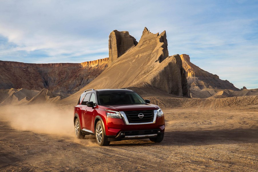 An image of a 2022 Nissan Pathfinder parked outdoors, in the sand..