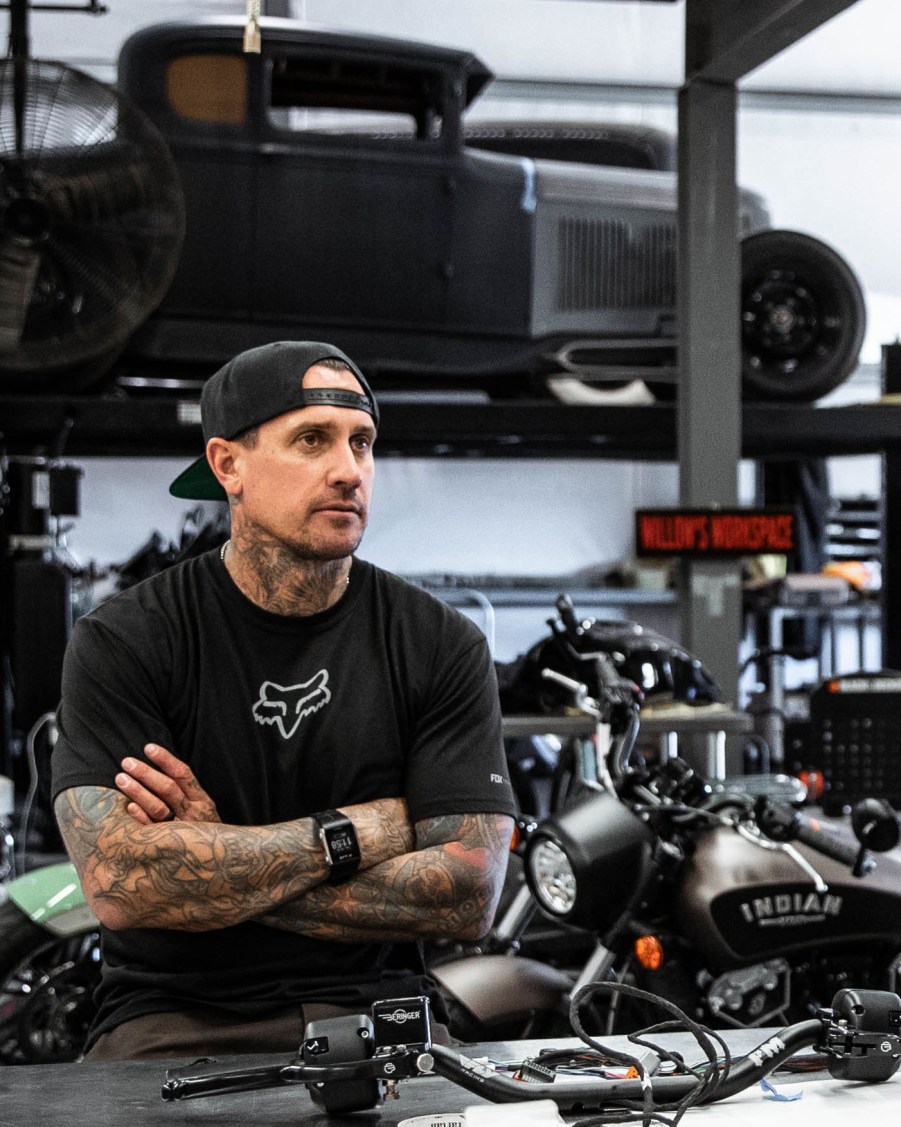 Carey Hart in his workshop garage with a hot rod on a lift