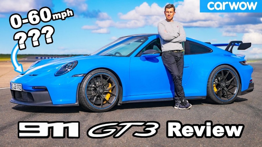 Carwow host Mat Watson with a blue 2022 Porsche 911 GT3 on a racetrack