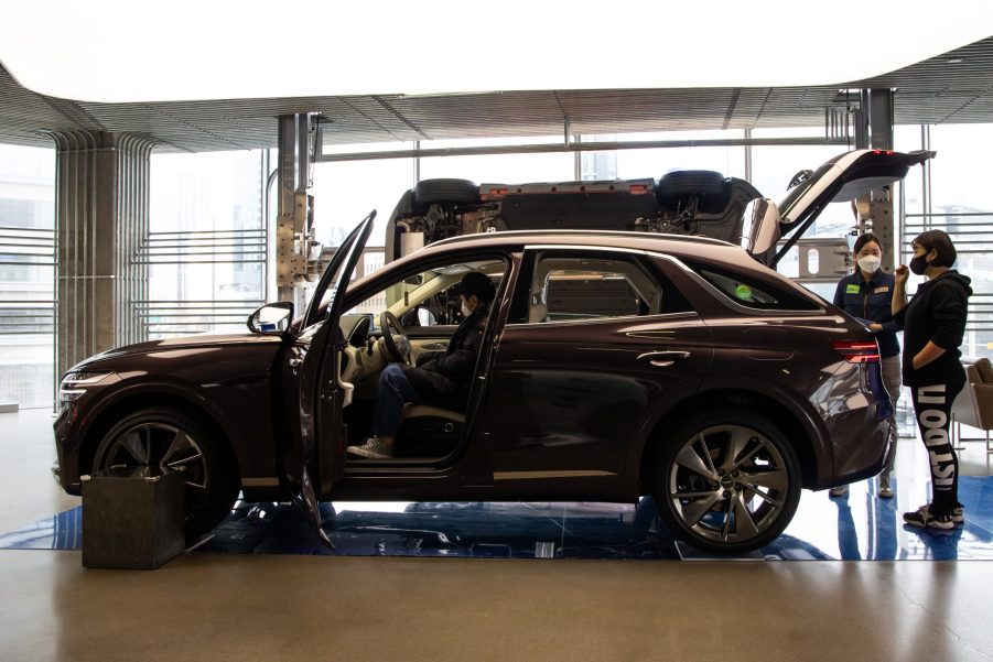 An employee assists a customer, right, standing next to a Hyundai Motor Co. Genesis GV70 sport utility vehicle (SUV) on display at the company's Motorstudio showroom in Seoul, South Korea