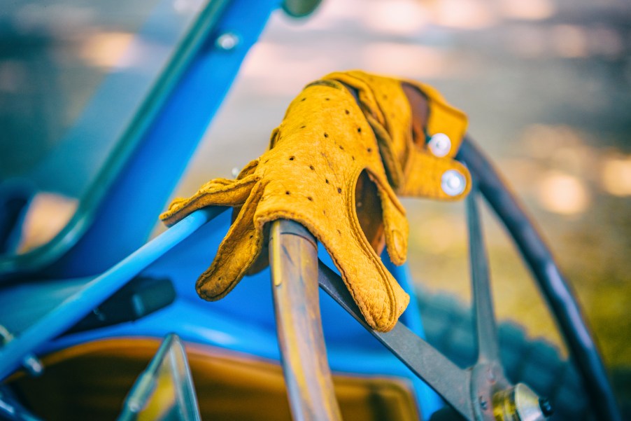 Yellow leather driving gloves on the steering wheel of a Bugatti Type 43 classic sports car of the 1920s on display at the 2019 Concours d'Elegance at palace Soestdijk on August 25, 2019, in Baarn, Netherlands