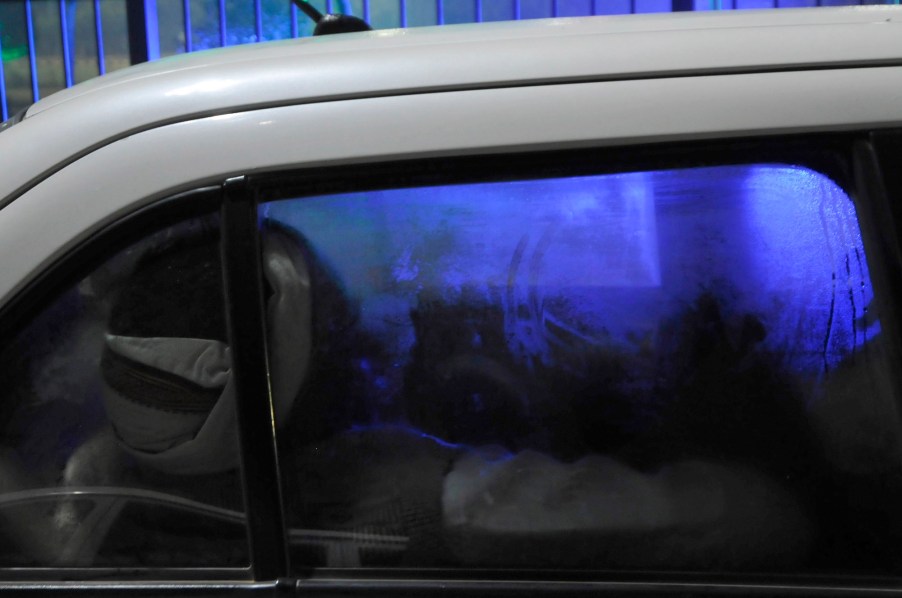 A person sleeping in a white car with fogged-up windows. Living in your car can be dangerous.