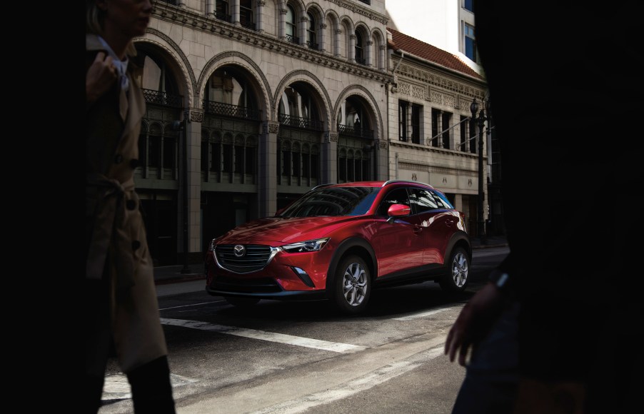 A red 2021 Mazda CX-3 Sport crossover SUV parked outside a stone building with arched windows