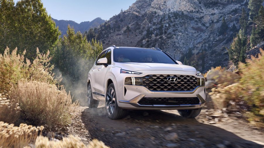 A white 2021 Hyundai Santa Fe driving over a gravel trail in the mountains