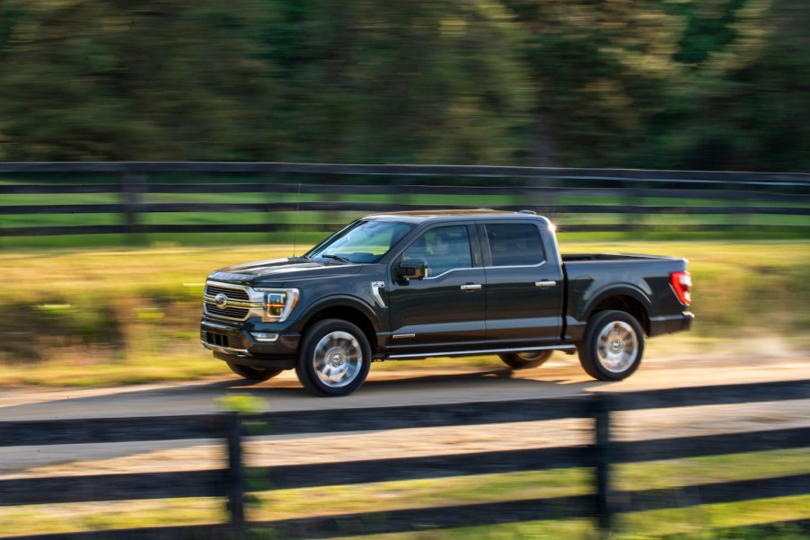 A dark 2021 Ford F-150 driving down a field lined road