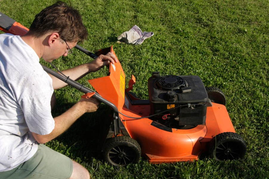 A man performing maintenance on a lawn mower