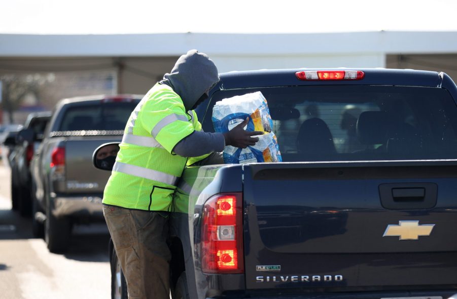 A worker with Houston Public Works loads a case of water into the truck bed of a Chevy Silverado during a mass water distribution