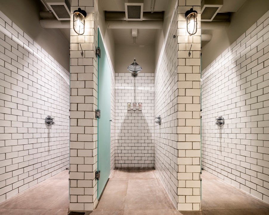 Gym showers with chic white subway tile walls and industrial lighting