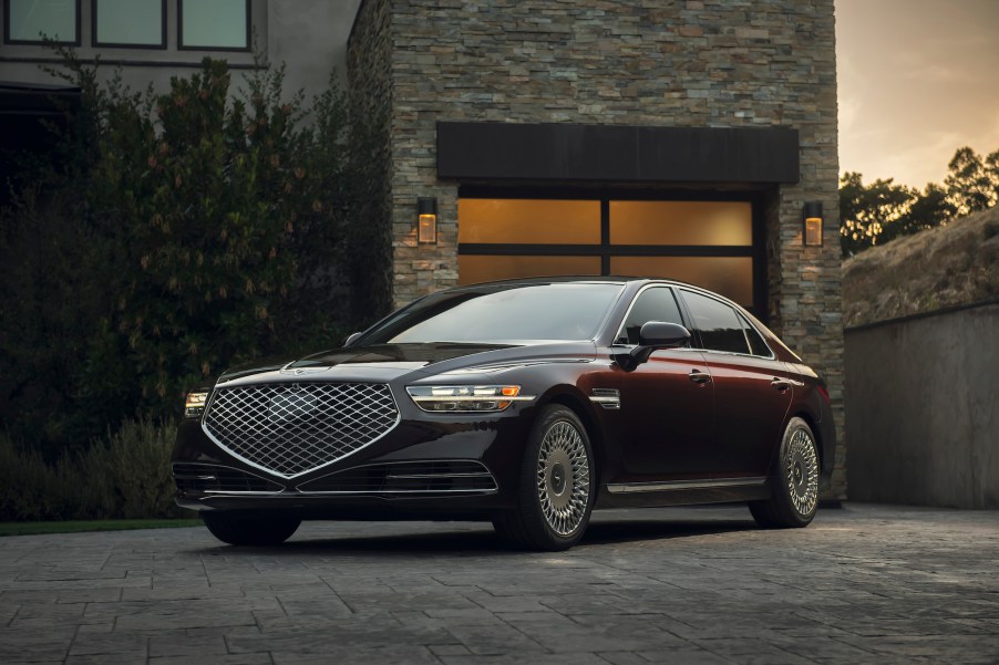 A dark-colored 2020 Genesis G90 luxury sedan parked outside a modern brick house