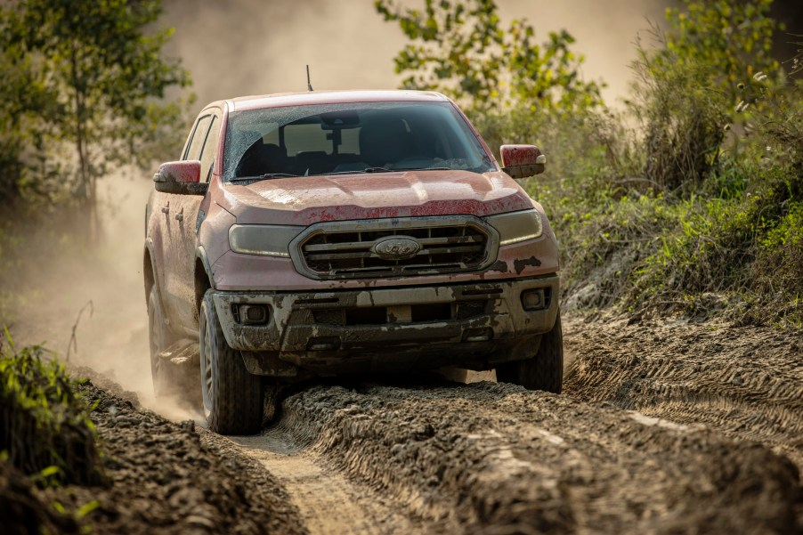 A mud-covered 2021 Ford Ranger Tremor Lariat compact pickup truck navigates an off-road trail