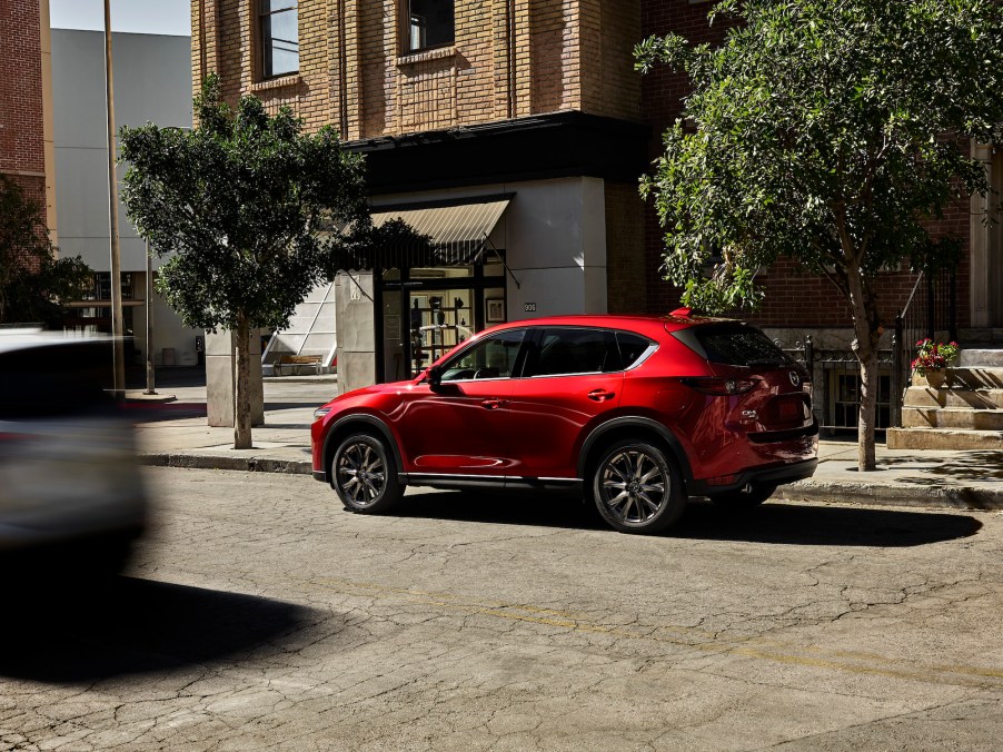 A red metallic 2021 Mazda CX-5 compact SUV parked on a city street on a sunny day