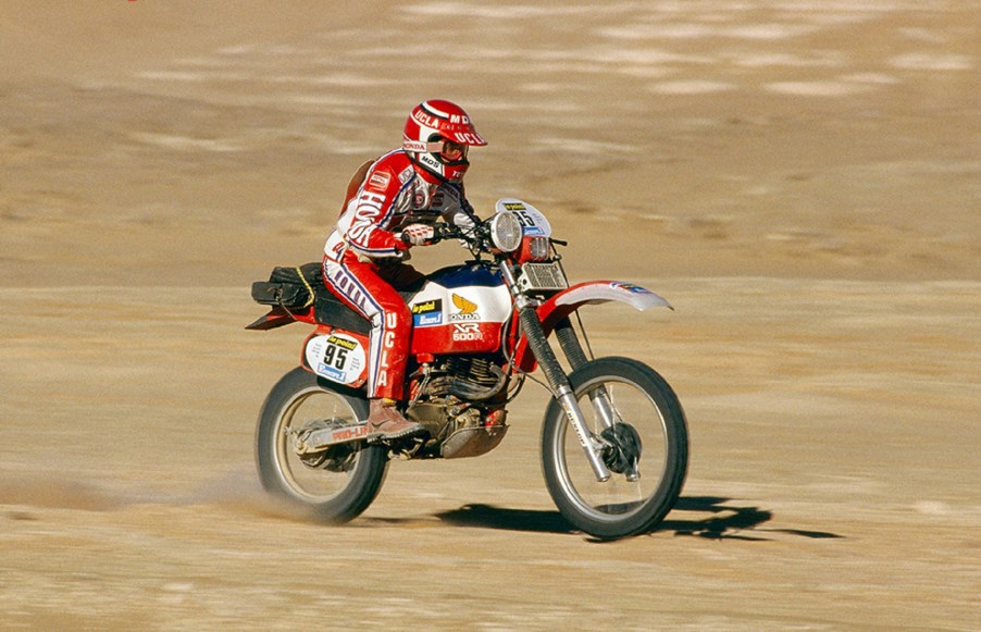 Red-clad Cyril Neveu on the red-and-white 1982 Honda XR500R Dakar Rally bike racing through the desert