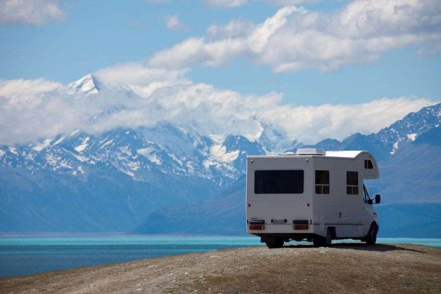 A white RV parked next to a bright blue mountain lake