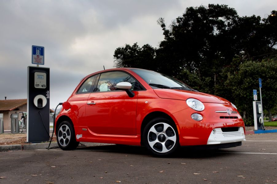 A red Fiat 500e plugged in and charging