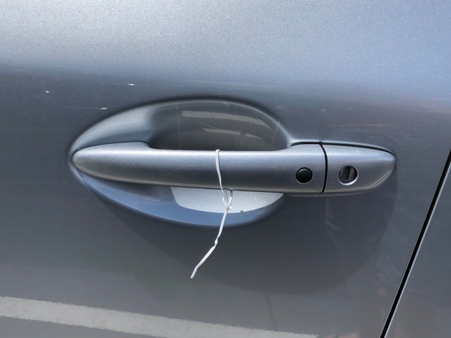 A white wire tied to a silver car door handle