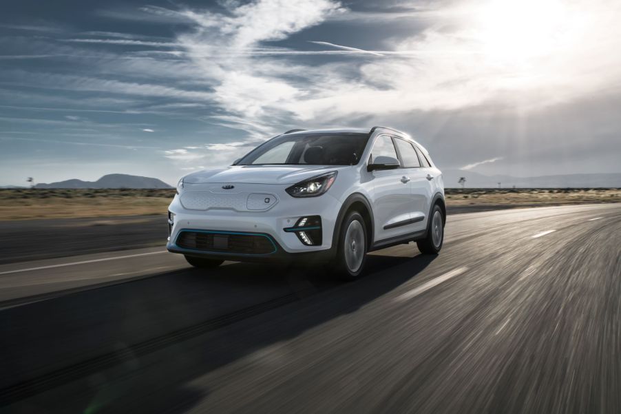 A white 2020 Kia Niro EV driving on a highway on a cloudy day in a plain with one small hill.