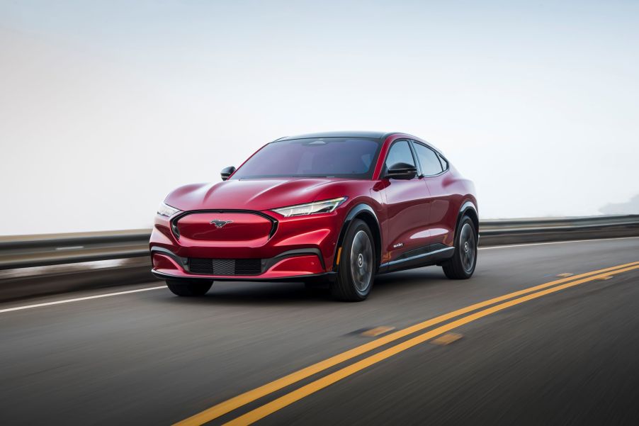 A red 2021 Ford Mustang Mach-E driving on a highway