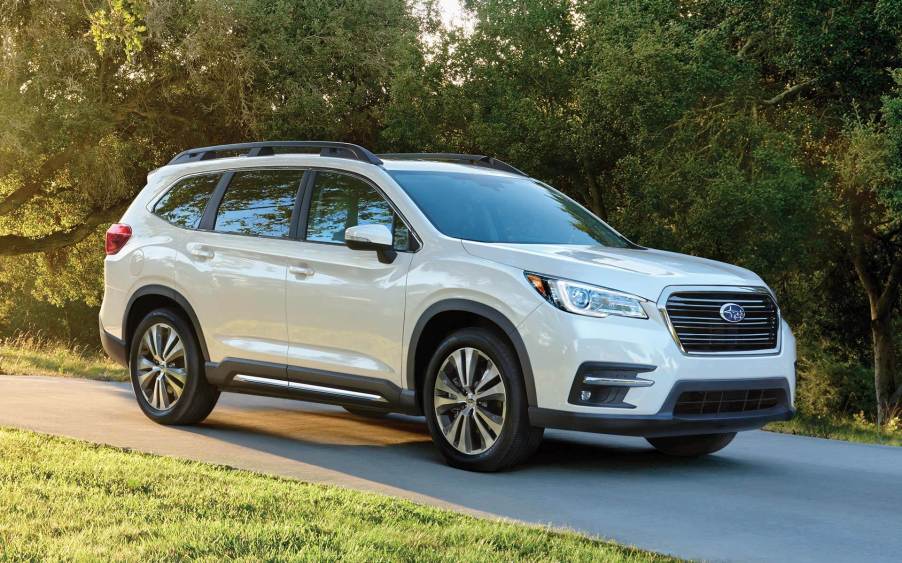 A white 2021 Subaru Ascent SUV parked on a trail near a grass field and forest