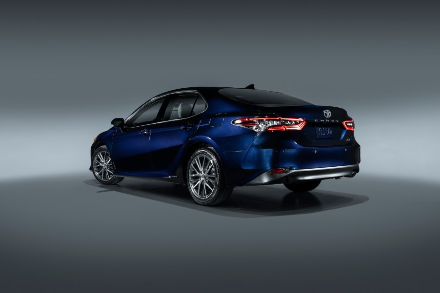 A deep-blue metallic 2021 Toyota Camry midsize sedan parked in a studio with a gray backdrop