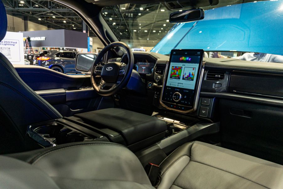 The front interior of a 2022 Ford F-150 Lightning with its folding table deployed at the 2021 Chicago Auto Show