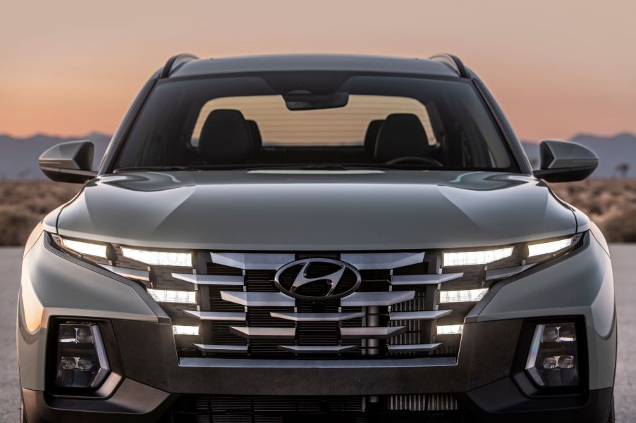 A front exterior shot of the 2022 Hyundai Santa Cruz with its headlights and grille lit up