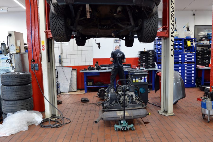 A car sits in a mechanic's shop with its engine removed