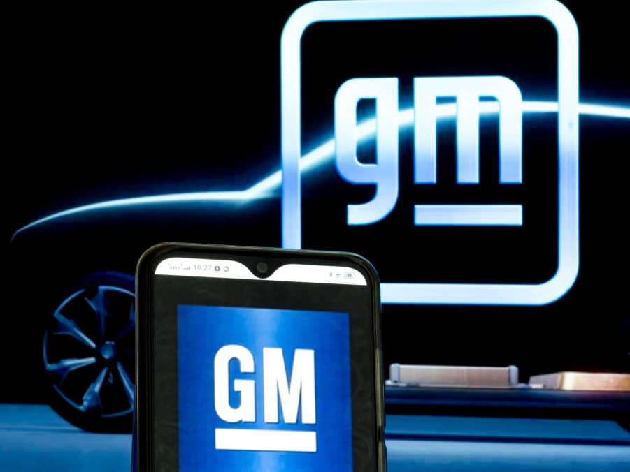 The old and new GM logos illuminated against a black backdrop