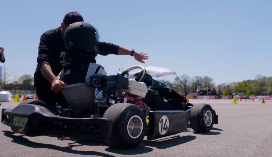 A man coaching a child on how to properly operate a go-kart