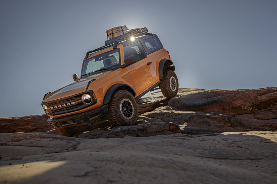 A yellow 2021 Ford Bronco off-roading over rocks