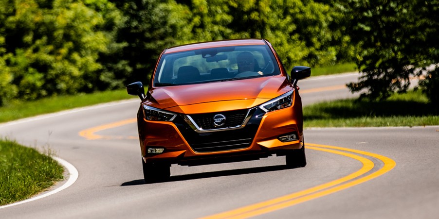 an orange 2021 Nissan Versa driving on a scenic winding road