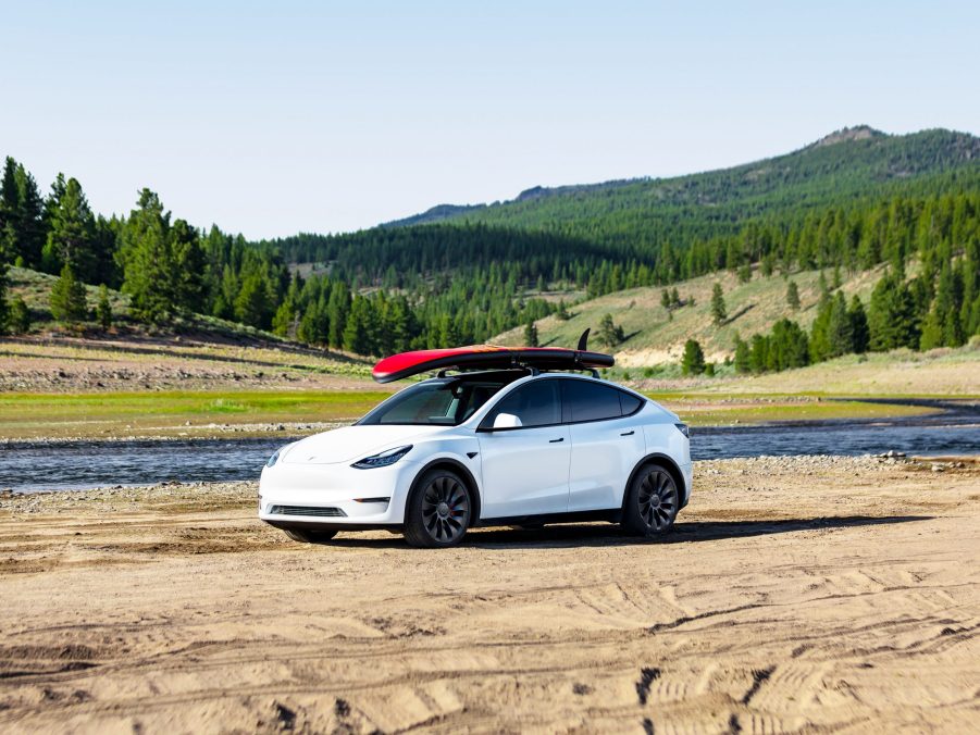 A Tesla Model Y with a surfboard mounted on the roof