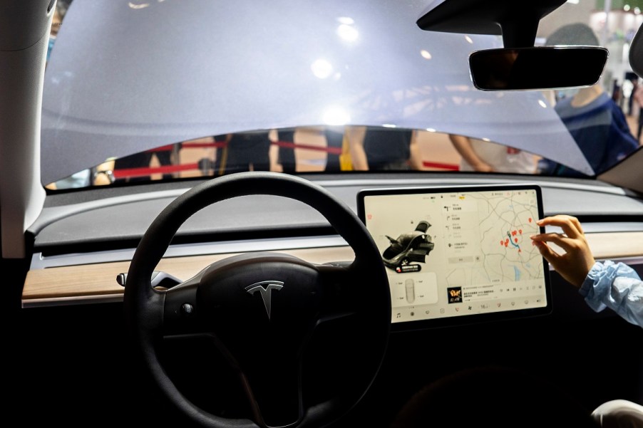 The steering wheel and screen of the inside of a Tesla.