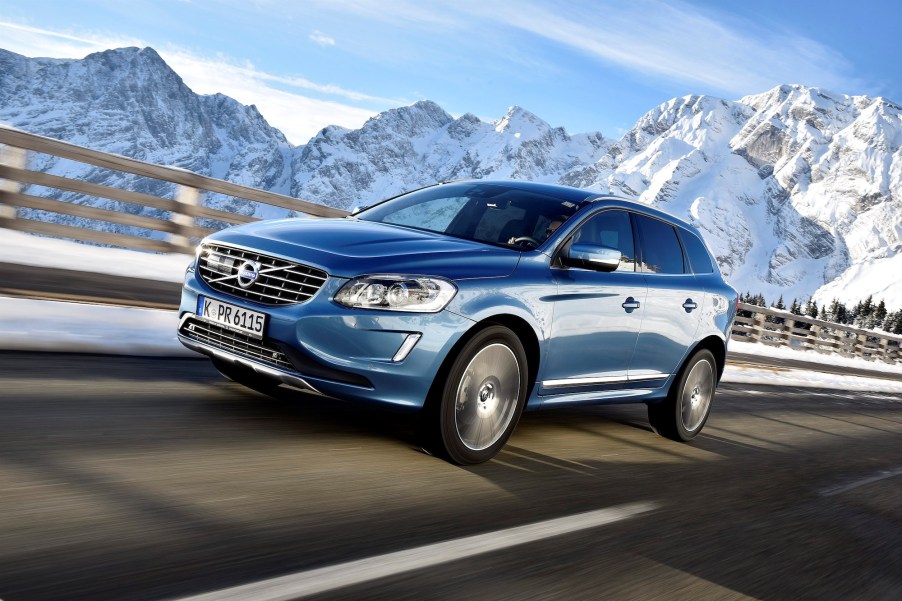 A 2017 Volvo XC60 T6 AWD luxury compact SUV travels on a highway past snow-capped mountains