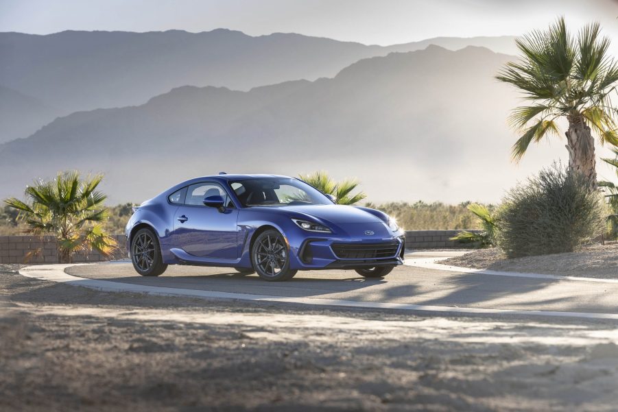 A blue Subaru BRZ among the palm trees in the desert